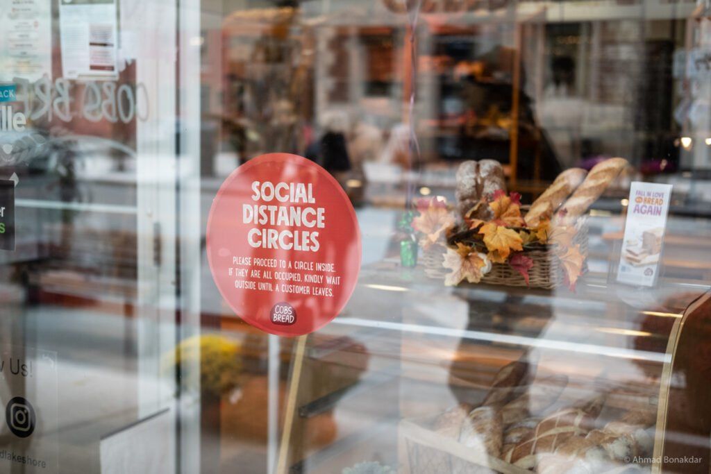 A shop window with a social distancing sign