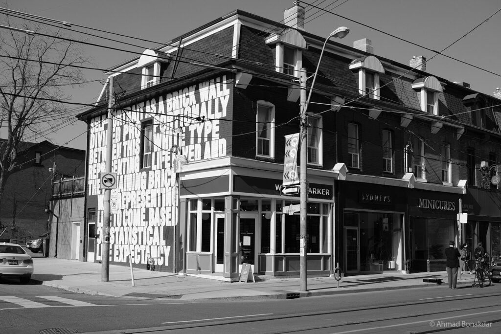 Black and white street corner in Toronto with a mural-covered building
